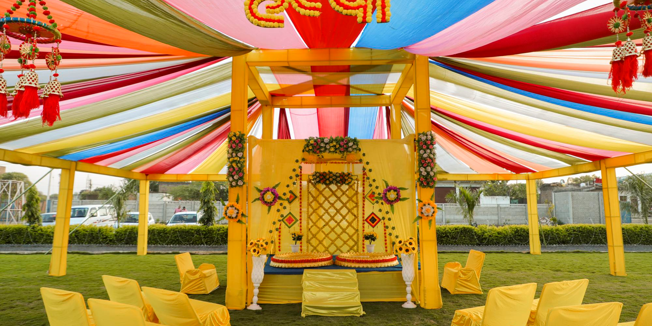 Haldi ceremony outdoor venue setup with yellow marigold canopy, colourful drapes, and cushioned seating for an Odia wedding in Kendrapara